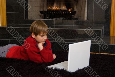 Boy at Fireplace on Computer.