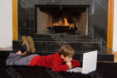 Boy at Fireplace on Computer.