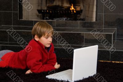 Boy at Fireplace on Computer.