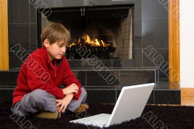 Boy at Fireplace on Computer.