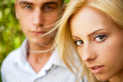 Portrait of beautiful young couple standing against green tree i