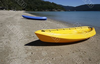 colorful kayaks on beach by turquoise waters