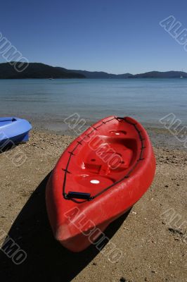 colorful kayaks on beach by turquoise waters