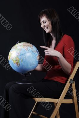 girl in red top pointing at globe