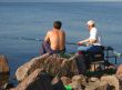 Seated men fishing off a shoreline